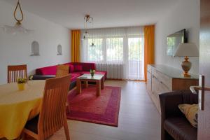 ein Wohnzimmer mit einem Tisch und einem roten Sofa in der Unterkunft Ferienwohnung Rosenstraße in Langenargen