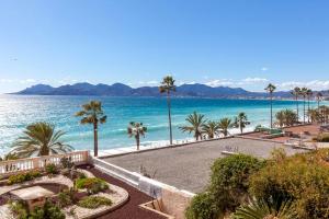 uma vista para uma praia com palmeiras e para o oceano em Résidence Saint Rémy 2 em Cannes