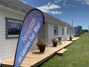 Cap-des-RosiersLes Cabines sur Mer的一座有蓝色标志的房子,上面写着新的建筑服务