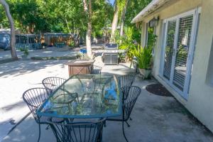 un patio con mesa de cristal y sillas en Key Largo Cottages, en Cayo Largo