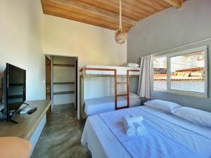 a bedroom with two bunk beds and a television at Pousada Primeira Praia Suítes in Morro de São Paulo +70 photos