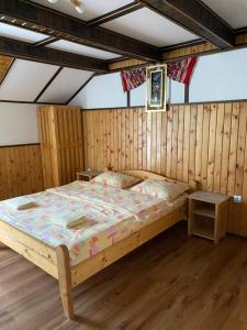a bedroom with a bed in a room with wooden walls at Pensiunea Puiu in Moieciu de Sus