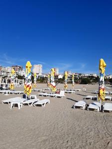 a beach with white lounge chairs and umbrellas at Casa Silvia in Constanţa