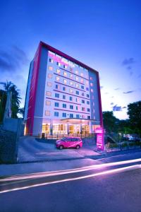 ボゴールにあるフェイヴホテル パドジャジャラン ボゴールの大きな建物の前に停車するピンク車