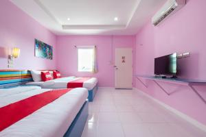 um quarto rosa com duas camas e uma televisão em OYO 1133 Koh Chang Baantalay Resort em Ko Chang
