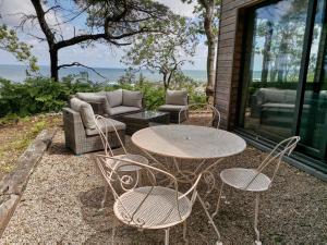 un patio con mesa, sillas y sofá en Au courtil des chênes marins, meublé 3 étoiles en Digosville