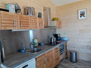 una cocina con armarios de madera y fregadero en Au courtil des chênes marins, meublé 3 étoiles en Digosville
