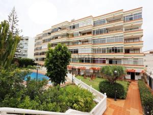 a large apartment building with a garden in front of it at Calm, Cosy and Bright apartment renovated in playa del ingles- WiFi free in Playa del Ingles