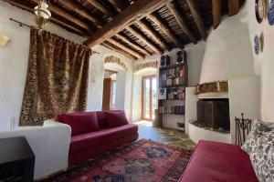 un soggiorno con divano viola e camino di The Old Stone Cottage a Karistos
