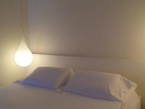 una cama con sábanas blancas y una luz en ella en Shalai, en Linguaglossa
