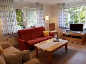 uma sala de estar com um sofá vermelho e uma mesa de centro em Haus Inge Ysker em Greetsiel