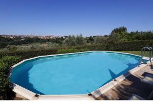 una gran piscina azul con 2 tumbonas alrededor. en Villa La Strega, en Siena