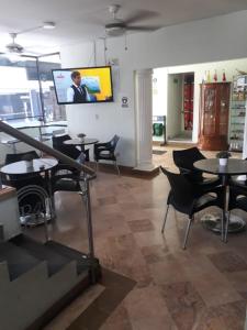 a room with tables and chairs and a tv on the wall at Hotel Ruiseñor Itagui in Itagüí