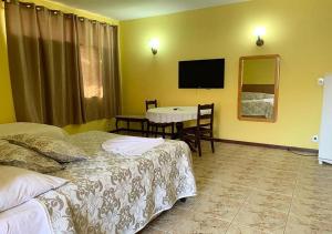 a hotel room with two beds and a table and a television at Hotel Avenida in Jacarèzinho