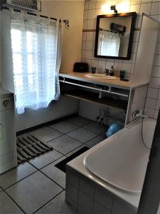 bagno con vasca, lavandino e specchio di Appartements - Le Mas des Oliviers a Richerenches