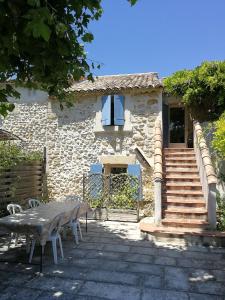 a stone house with a table and a table and chairs at Appartements - Le Mas des Oliviers in Richerenches