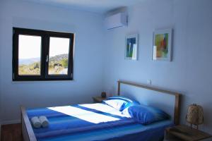 een blauwe slaapkamer met een bed en een raam bij Villa Zlatno Sunce in the hills near Trogir in Vrsine