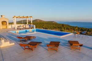 een zwembad met stoelen en een tafel bij Villa Zlatno Sunce in the hills near Trogir in Vrsine