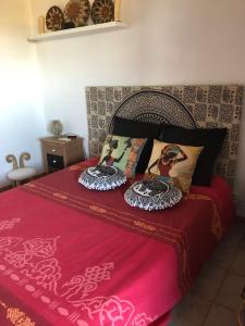 ein Bett mit einer roten Decke und Kissen darauf in der Unterkunft logement zen sur la colline aux mimosas in Hyères