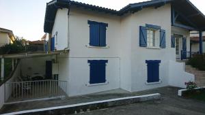 een wit huis met blauwe deuren en ramen bij Appartement T3 3 étoiles à 4 km de la plage in Tarnos