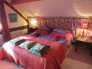 a bedroom with a bed with red sheets and pillows at Le Chant Des Fees in Notre-Dame-de-Courson