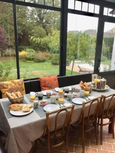 a table with plates of food and drinks on it at Maison d'Hôtes Joussaume Latour in Château-Thierry