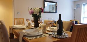 einen Esstisch mit einer Flasche Wein und Blumen in der Unterkunft Elite luxury apartment in Birmingham