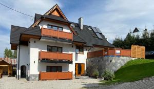 a white house with a black roof at Apartamenty Na Przełaj - LUX - zewnętrzna sauna fińska i zewnętrzne gorące jacuzzi - cały rok! in Poronin
