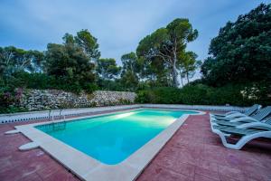 a swimming pool with two chairs next to a stone wall at VILLA NUEVA in Cala Galdana