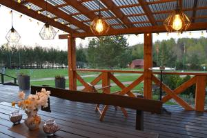 a wooden table with a bench on a deck with lights at Sodyba Ciciriai in Vėdariai