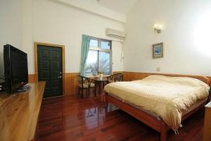 ein Schlafzimmer mit Bett, Fernseher und Tisch in der Unterkunft 千禧山莊民宿 in Fengbin