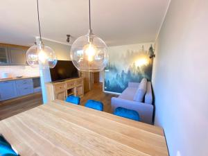 uma cozinha e sala de estar com uma mesa e cadeiras azuis em Apartament Zdrojowa z tarasem i ogrodem em Polańczyk