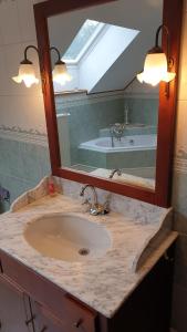 een badkamer met een wastafel, een spiegel en een bad bij Le basecamp des sommets in Stavelot