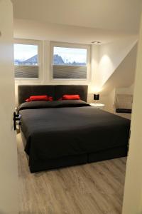 um quarto com uma cama preta e 2 janelas em Minsu Hotel em Mülheim an der Ruhr