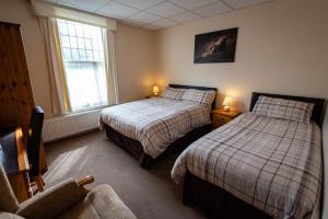 a bedroom with two beds and a chair and a window at Aarondale Guest House in Hartlepool