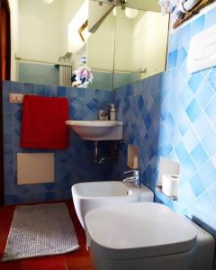 bagno piastrellato blu con servizi igienici e lavandino di Villetta Punta Granata Santa Marina Salina a Santa Marina Salina