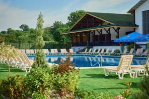a pool with chairs and umbrellas in a yard at Hotel Lubenska Sloboda in Vilʼshanka