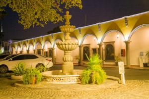 uma fonte em frente a um edifício à noite em Hotel Cosmos Don Carlos em Mexicali