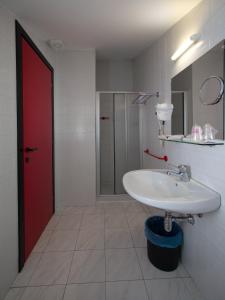 a bathroom with a white sink and a red door at Hotel Versailles in Colorno