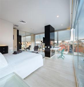 Schlafzimmer mit einem großen weißen Bett und einem Schreibtisch in der Unterkunft The Click Clack Hotel Bogotá in Bogotá