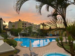 - une piscine avec un palmier et des bâtiments dans l'établissement La Quinta Suite Home Share, à Santa Úrsula