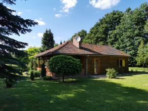 una pequeña casa de madera en un campo de hierba en Agroturystyka Sielanka nad Stawem, en Turawa