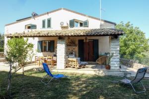 ein kleines weißes Haus mit blauen Stühlen im Hof in der Unterkunft Villa Ananda homestay & yoga retreat in Palazzolo Acreide
