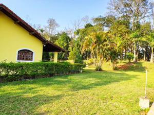 um quintal com uma casa amarela e árvores em Casa de Campo Lazer Completo Paraíso de Reservas Naturais em Sp em Ibiúna