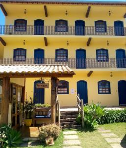 an old yellow building with blue doors and stairs at Pousada Luz do Sol in Carrancas