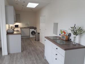 uma cozinha com armários brancos e uma bancada em Colebrook Cottage em Isle of Whithorn