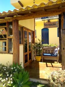 a porch of a house with a bench and a sign at Pousada Luz do Sol in Carrancas