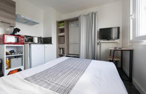 um quarto com uma cama branca e uma televisão em STUDIO A 300 METRES DE LA GARE et 25 MINUTES DE PARIS EN TRAIN em Melun