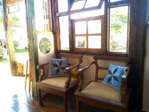 a pair of chairs in a room with windows at Pousada Luz do Sol in Carrancas
