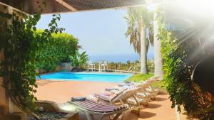 a group of lounge chairs next to a swimming pool at Exclusive Villa Golf Private Pool in Adeje